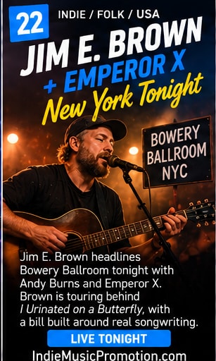 Singer-songwriter performing with acoustic guitar under warm stage spotlight.