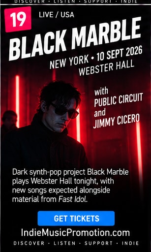 Chris Stewart of Black Marble in sunglasses illuminated by red neon bars.